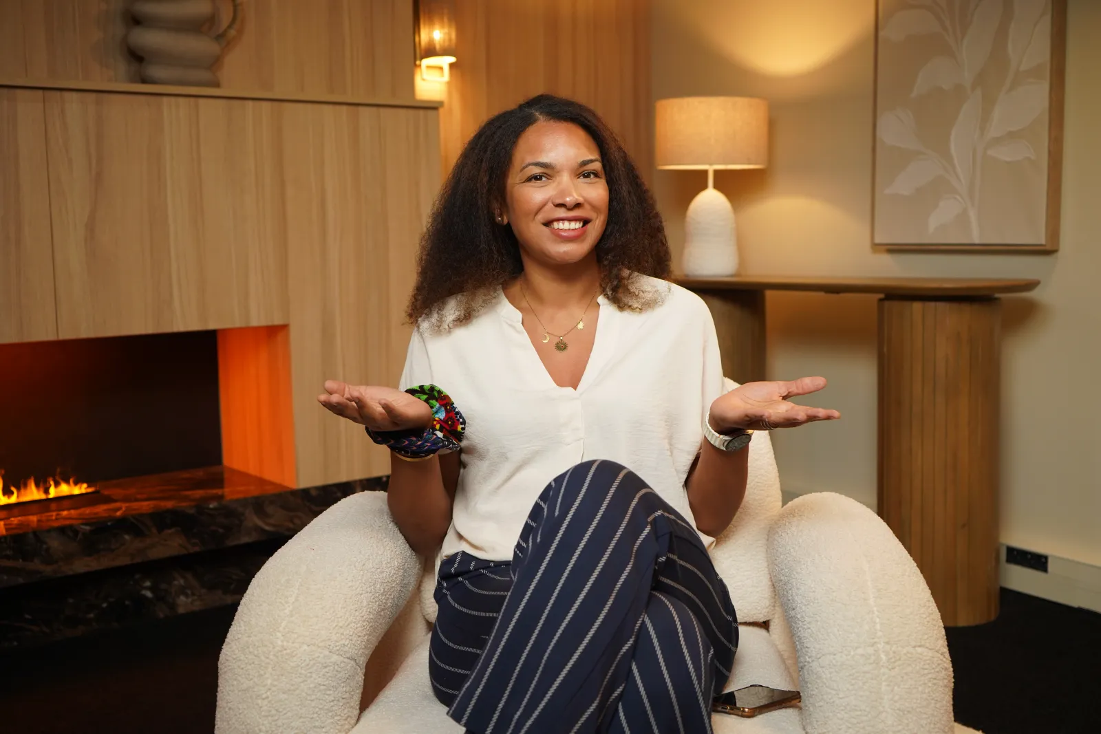 Guest in a bouclé armchair by the Cosy Cream fireplace