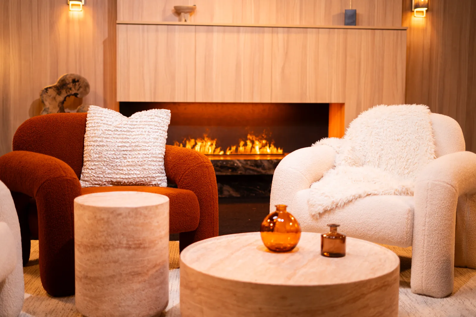 Bouclé armchairs and lit fireplace of the Cosy Cream studio