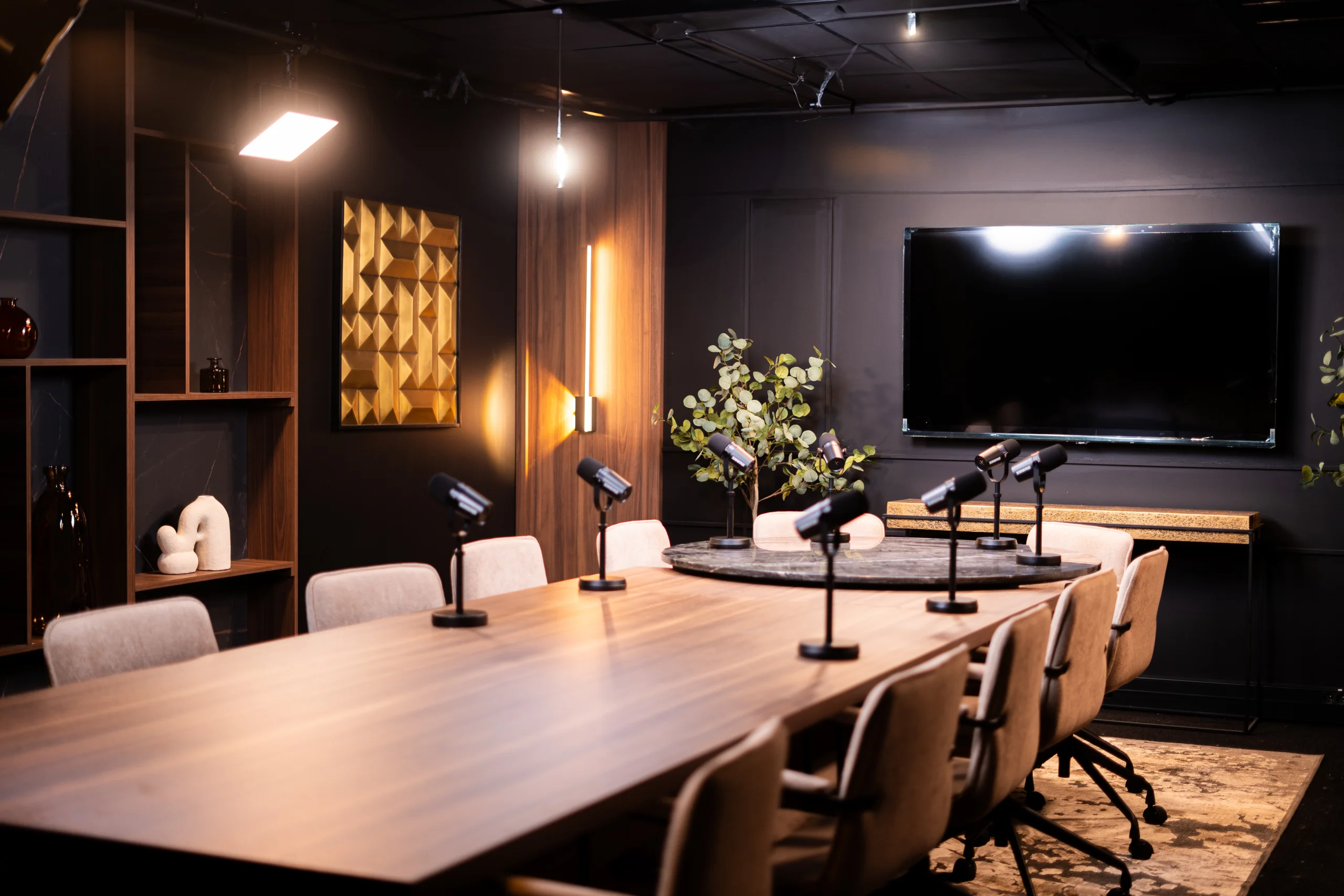 Recordia's Board Room studio: large wooden table, microphones and screen under the spotlights