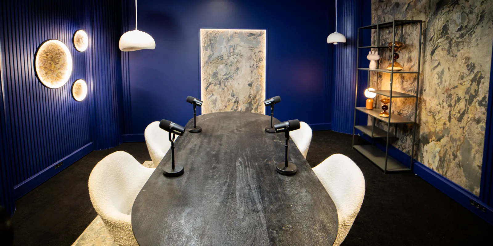 Studio Galaxy de Recordia : table noire, fauteuils crème et panneaux bleu nuit sous les lunes lumineuses